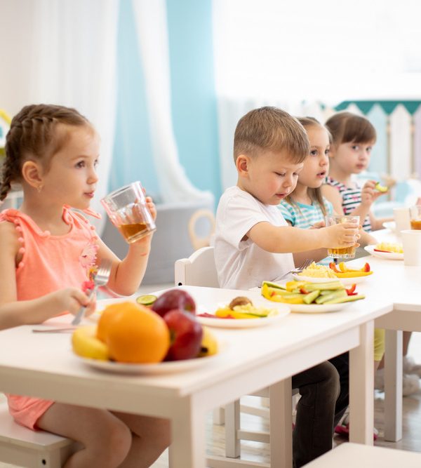 Group of children eating healthy food in day care centre